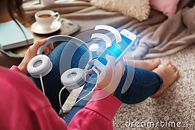 Woman with headphones and smartphone using free Wi-Fi at home Stock Photo