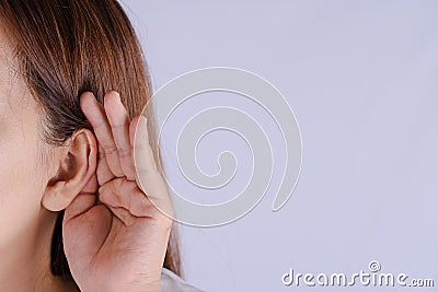 Woman hearing loss or hard of hearing and cupping her hand behind her ear isolate grey background, Deaf concept Stock Photo