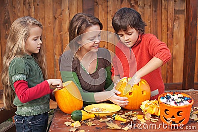 Woman helping kids to carve jack-o-lanterns Stock Photo