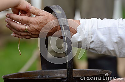 Woman helps a child dip a candle wick into molten beeswax Stock Photo