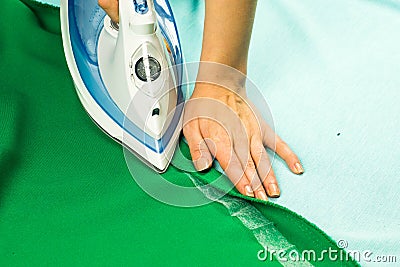 Woman hemming, shortening green courtain fabric with an adhesive iron-on hemming tape Stock Photo