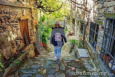 Woman with her back to walking through a narrow alley with stone houses in the village of Patones de Arriba, Madrid. Stock Photo