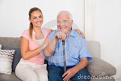 Woman With Her Disabled Father Sitting On Sofa Stock Photo