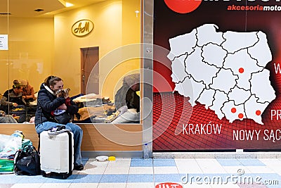 A woman with her dog and a suitcase sits close to a map of Poland as refugees from Ukraine are seen inside a mall turned refugees Editorial Stock Photo