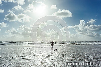 Woman and her dog walking at the beach at sunset or sunrise Stock Photo