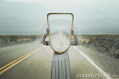 A woman hides holding a mirror in front of her face introspection path concept Stock Photo
