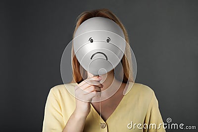 Woman hiding behind balloon with sad face on grey background. Depression concept Stock Photo