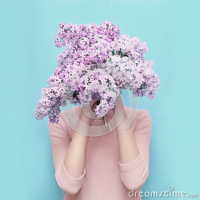 Woman hiding head in bouquet lilac flowers over colorful blue Stock Photo