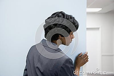 Woman hiding peering round corner Stock Photo