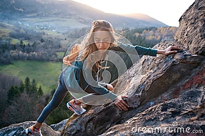 Woman hiker climbed on the cliff and looks confused Stock Photo