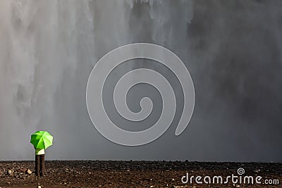Woman Hiker WIth Green Umbrella Next to a Waterfall Stock Photo