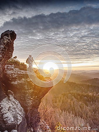 Woman hiker set tripod with camera on exposed rocky summit Stock Photo