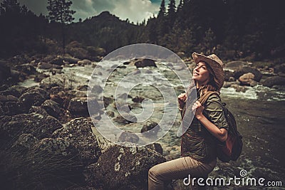 Woman hiker standing near wild mountain river. Stock Photo