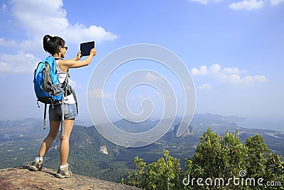 Woman hiker taking photo with digital camera at mountain peak Stock Photo