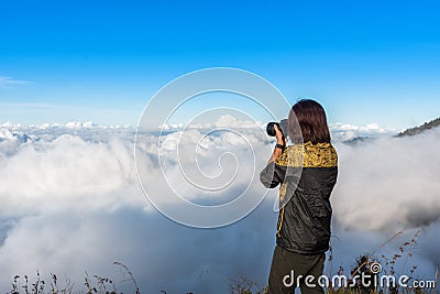 Woman hiker wear jacket, taking photograph, enjoy and happy with mountain top view after finished climbing at mount Rinjani. Editorial Stock Photo