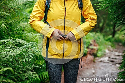 Female tourist is fastening buckle on backpack strap at forest trekking trail Stock Photo