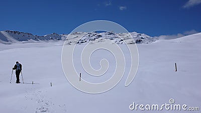 Woman hiking into the winter wilderness of the Alps of Switzerland with snowshoes on a beautiful day Stock Photo