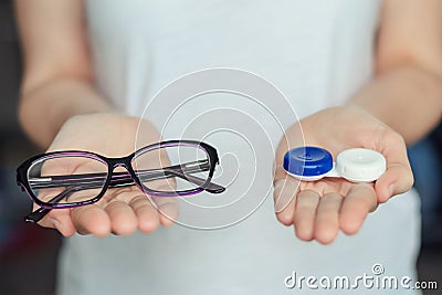 Woman hold contact lenses and glasses in hands. concept of choice of vision protection Stock Photo
