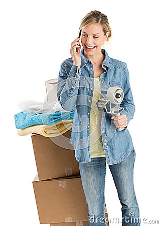 Woman Holding Adhesive Tape While Using Phone By Stacked Boxes Stock Photo