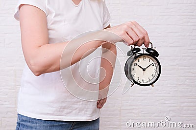 Woman holding an alarm clock showing 10 oclock, people should value and appreciate time Stock Photo