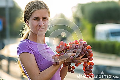 A woman holding big cluster of red juicy grapes in her hand Stock Photo