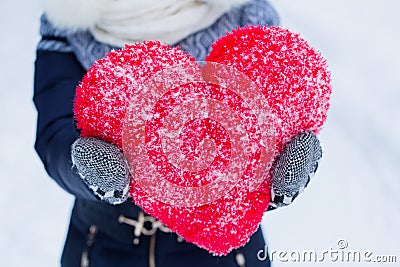 Woman is holding big heartshape pillow outdoors in winter. Stock Photo