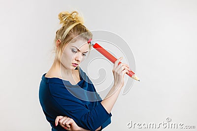 Woman holding big oversized pencil thinking about something Stock Photo