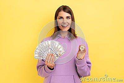 Woman holding bitcoin and big fan of dollar bills, exchange crypto currency. Stock Photo