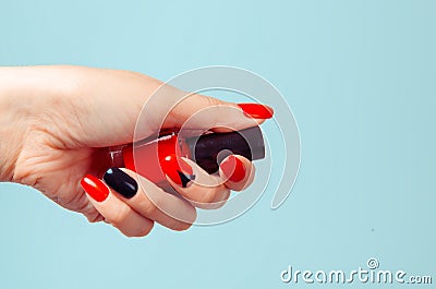Woman holding bottle of nail polish. Art Manicure. Modern style red black Nail Polish with triangle. Stylish Colorful stiletto Stock Photo