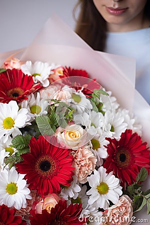A woman is holding a bouquet of gerbera flowers. The florist creates a red beautiful bouquet of mixed flowers. Stock Photo