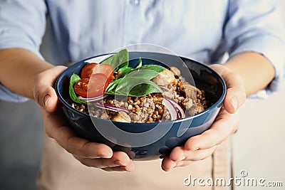 Woman holding bowl of delicious buckwheat porridge with vegetables and mushrooms Stock Photo