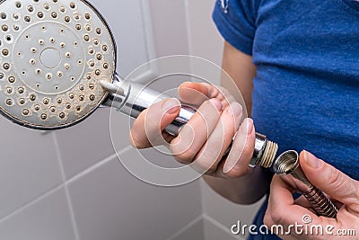 Woman is holding a broken shower sprinkler head in her hands and changes to a new one Stock Photo