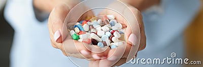 Woman holding bunch of colourful medications on palm for treatment Stock Photo