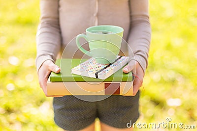 Woman holding chamomile tea and stacked books Stock Photo