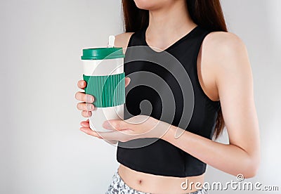 Woman holding a coffee cup in hands with exercises girls background. Blank mug for design. Stock Photo