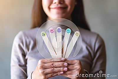 A woman holding hand draw happy emotion faces on wooden stick Stock Photo