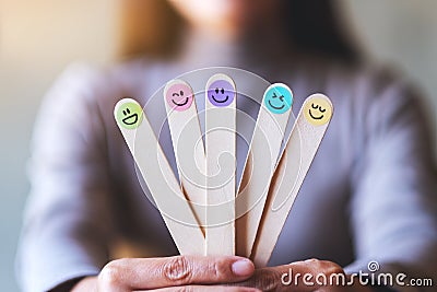 A woman holding hand draw happy emotion faces on wooden stick Stock Photo