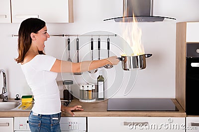 Woman Holding Cooking Pot With Fire Stock Photo