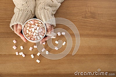 Woman holding cup of aromatic cacao with marshmallows on wooden background, top view Stock Photo