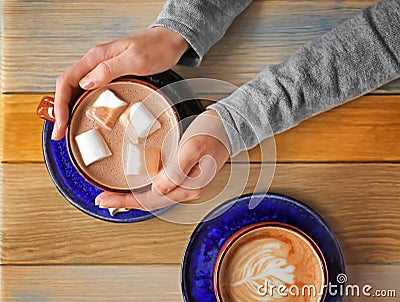 Woman holding cup of aromatic cacao at wooden table, top view Stock Photo