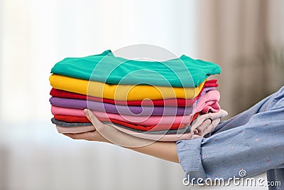 Woman holding folded clean clothes indoors. Laundry day Stock Photo