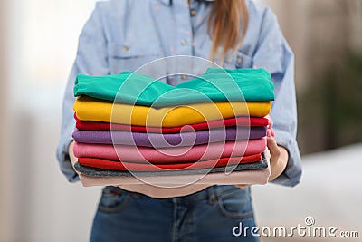 Woman holding folded clean clothes indoors, closeup. Stock Photo