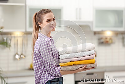 Woman holding folded clean towels in kitchen Stock Photo