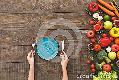 Woman holding fork, knife, in front of her plate, vegetables Stock Photo