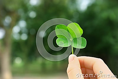 Woman holding four-leaf clover outdoors Stock Photo