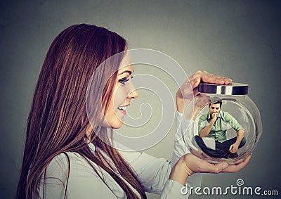 Woman holding a glass jar with imprisoned man in it Stock Photo