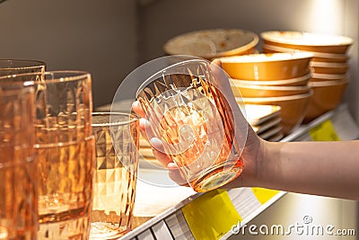 Woman holding glass from a shelf in homeware store. Stock Photo