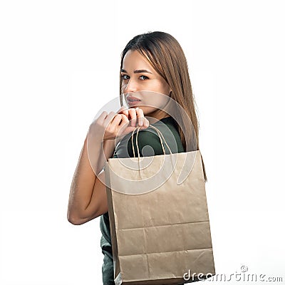 Woman is holding grocery shopping bag on white background. Young girl is holding light brown shopping bag behind back. Stock Photo