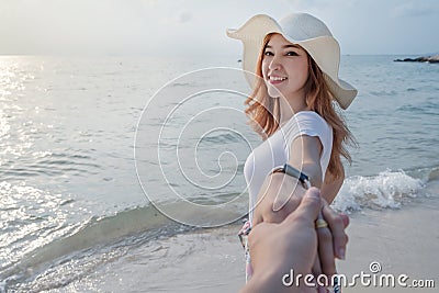 Woman holding hand of her boyfriend while leading to sea beach Stock Photo