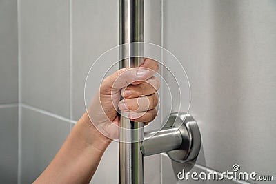 Woman holding on handrail in toilet. Stock Photo